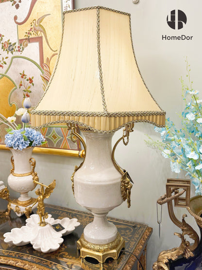 It pairs with a soft beige fabric shade, trimmed with intricate braided edging and tassel details