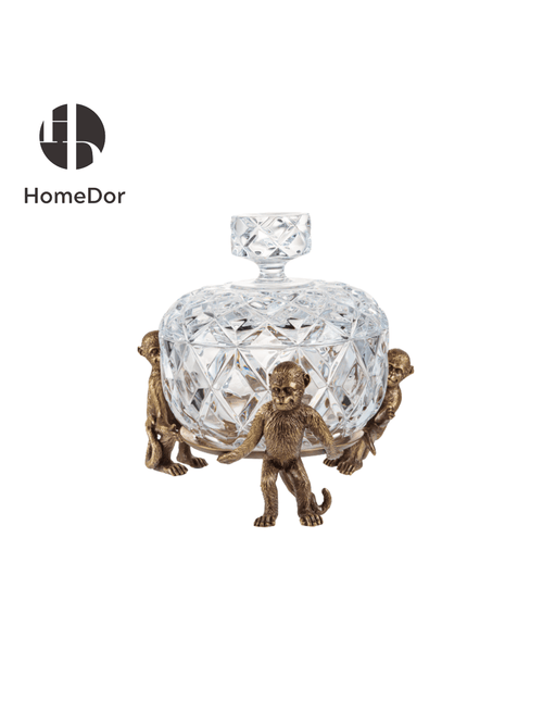Decorative crystal bowl with bronze monkey figurines on a white background, featuring the HomeDor brand.
