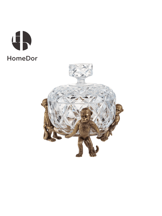 Decorative crystal bowl with bronze monkey figurines on a white background, featuring the HomeDor brand.