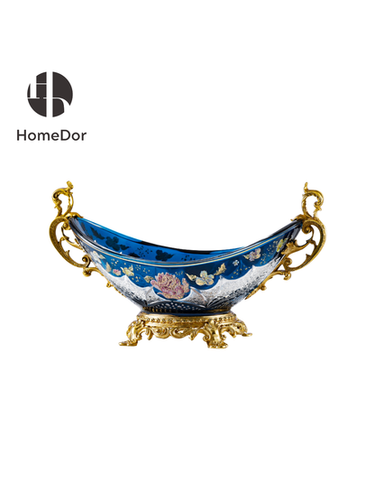 Inspired by the romance of Belle Époque decorative arts, each piece combines luminous Aurora Glass with intricate gilt mounts, creating a harmonious balance between elegance and imagination. The rich blue palette evokes twilight skies, while the golden floral motifs bring warmth and vitality, as though illuminated by a hidden moonlit glow.