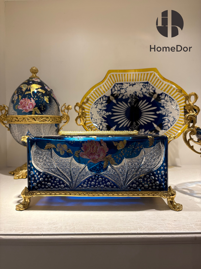 Inspired by the romance of Belle Époque decorative arts, each piece combines luminous Aurora Glass with intricate gilt mounts, creating a harmonious balance between elegance and imagination. The rich blue palette evokes twilight skies, while the golden floral motifs bring warmth and vitality, as though illuminated by a hidden moonlit glow.
Displayed together, the collection creates the atmosphere of a secret garden preserved in glass—one where flowers never fade, butterflies never depart, and beauty linger