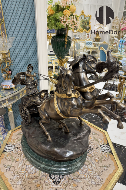 The piece rises from a rough-hewn rock formation, as though the chariot has just broken free of the ground itself, set on a base of green marble that grounds the whole composition and gives it the weight of a real collector's bronze rather than a decorative reproduction.