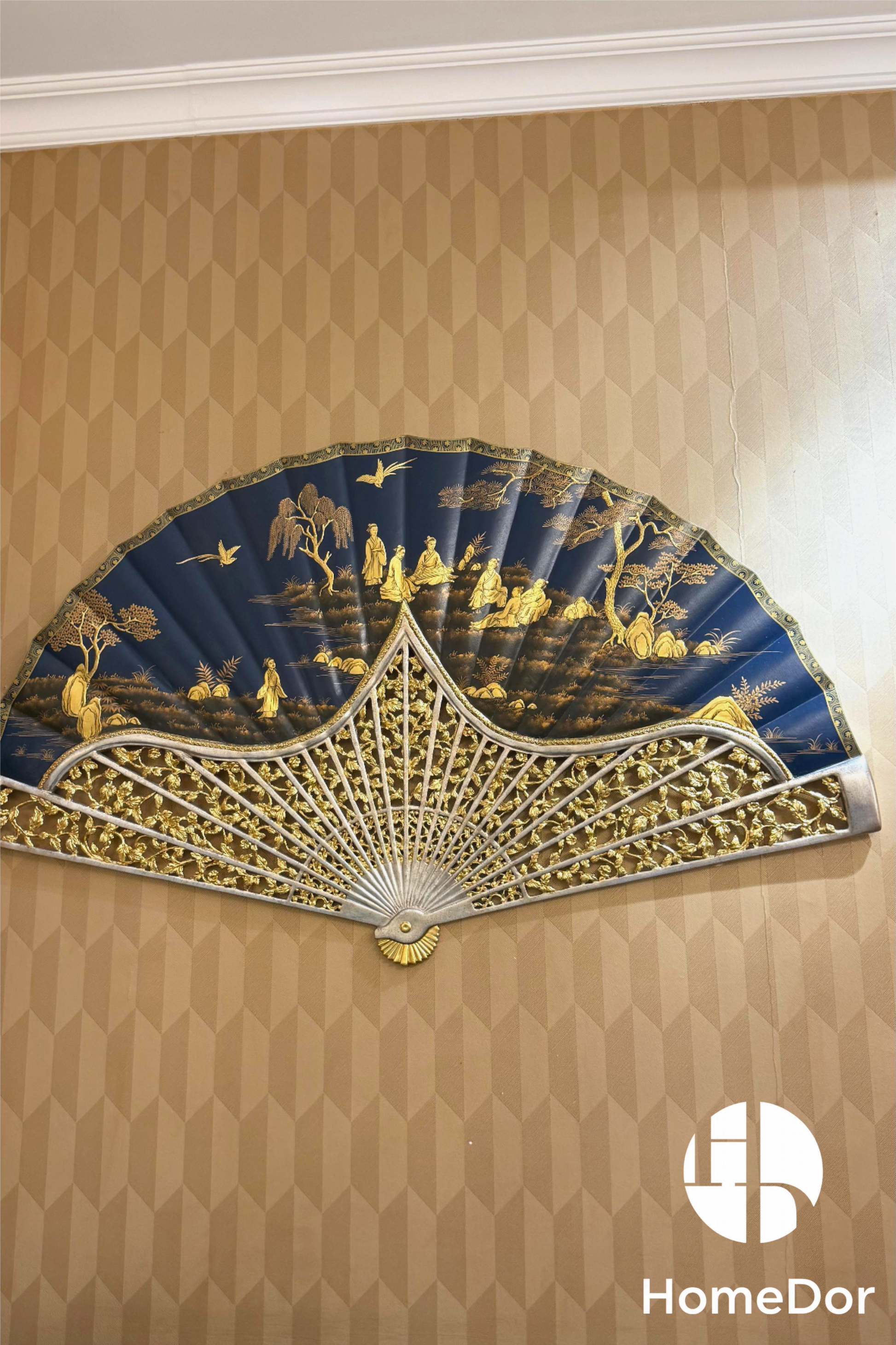 Grand Royal Blue Chinese Figure Scenery Gold Painted Fan Wall Art that blends imperial elegance with traditional Chinese artistry. Featuring intricate gold-painted figures amidst a serene landscape, set against a rich royal blue backdrop, this fan-shaped artwork is framed with ornate carved detailing, exuding a sense of regal sophistication
