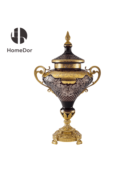The smaller urn is taller in proportion and more slender in line, its body tapering toward a pedestal mounted in acanthus leaves and a gilt base on scrolled feet. Made for a mantel, a console beneath a mirror, or a pedestal in an entrance hall, it brings the same drama to a more intimate scale.