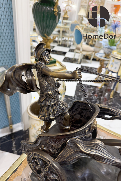 Rendered in deep bronze patina with gilt picked out along the harness, the wheel spokes, and the warrior's armor.