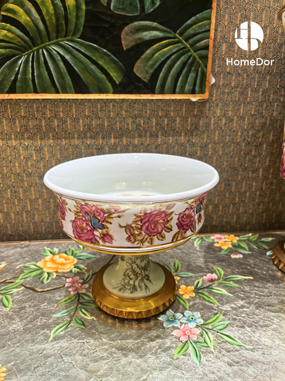 White porcelain compote with pink roses, blue butterflies, and pale green interior on gold pedestal base