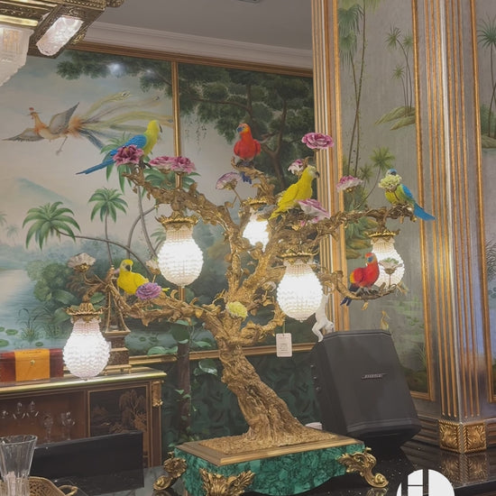a masterpiece that blends opulent craftsmanship with vibrant artistic detail. Featuring vividly colored parrots and blooming florals perched on an intricately sculpted bronze tree, this lamp is adorned with crystal-encrusted lanterns and set atop a malachite-inspired base.Crafted from copper, high-temperature porcelain, and malachite accents, it exudes a sense of royal elegance, making it a focal point in living rooms, bedrooms, or luxury lounges. 
