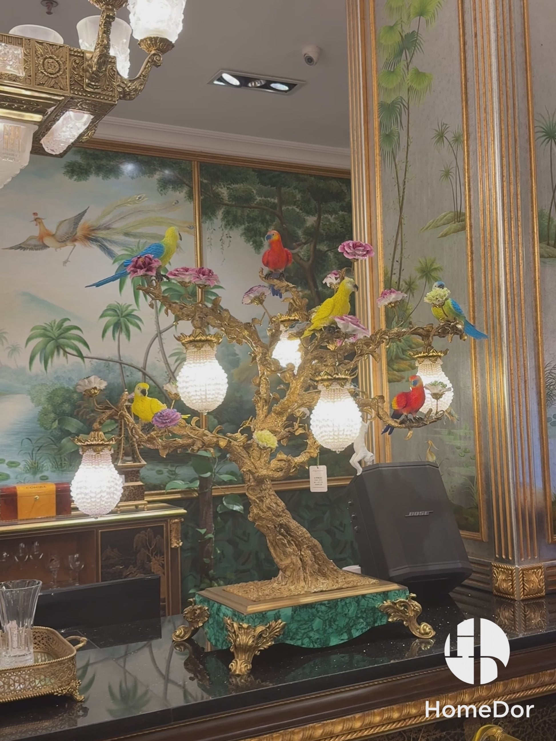 a masterpiece that blends opulent craftsmanship with vibrant artistic detail. Featuring vividly colored parrots and blooming florals perched on an intricately sculpted bronze tree, this lamp is adorned with crystal-encrusted lanterns and set atop a malachite-inspired base.Crafted from copper, high-temperature porcelain, and malachite accents, it exudes a sense of royal elegance, making it a focal point in living rooms, bedrooms, or luxury lounges. 