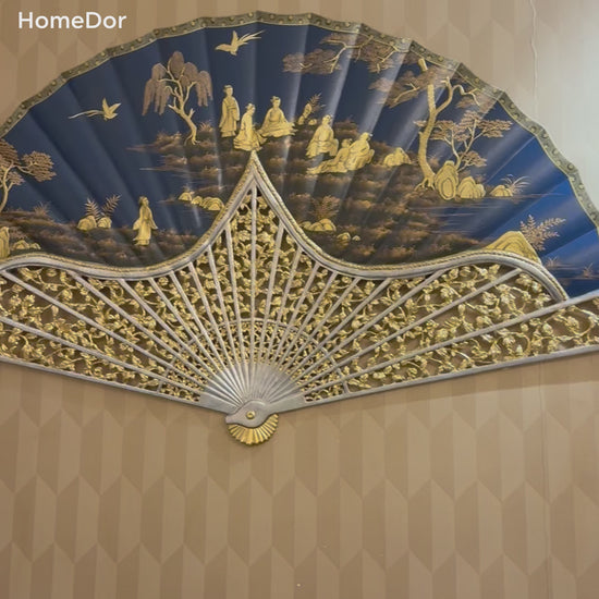 Grand Royal Blue Chinese Figure Scenery Gold Painted Fan Wall Art that blends imperial elegance with traditional Chinese artistry. Featuring intricate gold-painted figures amidst a serene landscape, set against a rich royal blue backdrop, this fan-shaped artwork is framed with ornate carved detailing, exuding a sense of regal sophistication